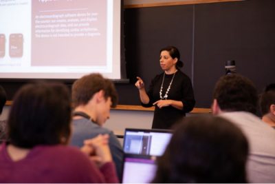 Female from Gilero lectures to a class of students, pictured in the foreground